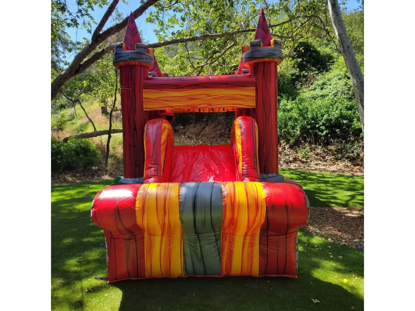 A red and yellow inflatable castle in the middle of a park.