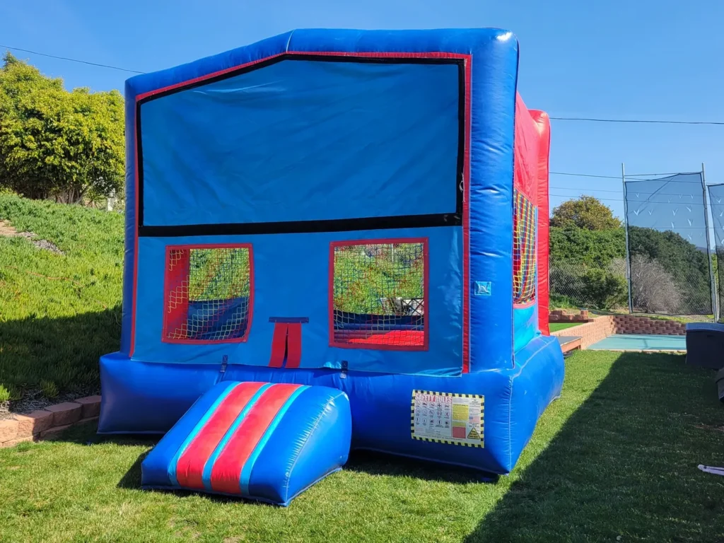 A blue and red bounce house in the grass.