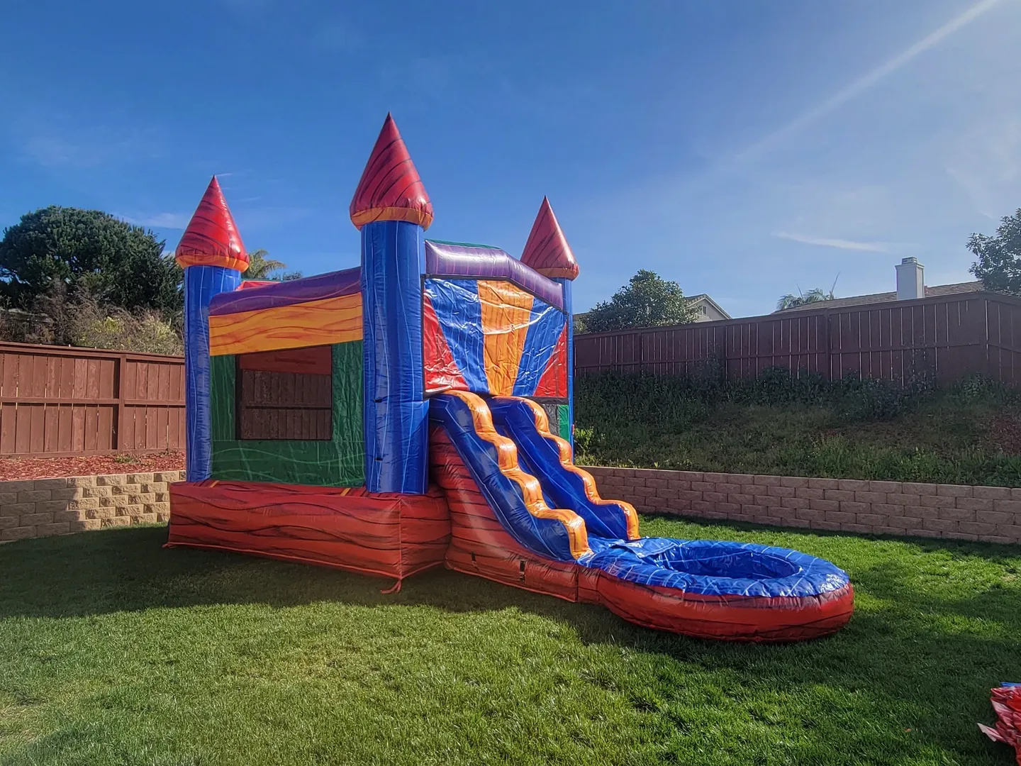 A bouncy castle with water slide in the middle of a yard.