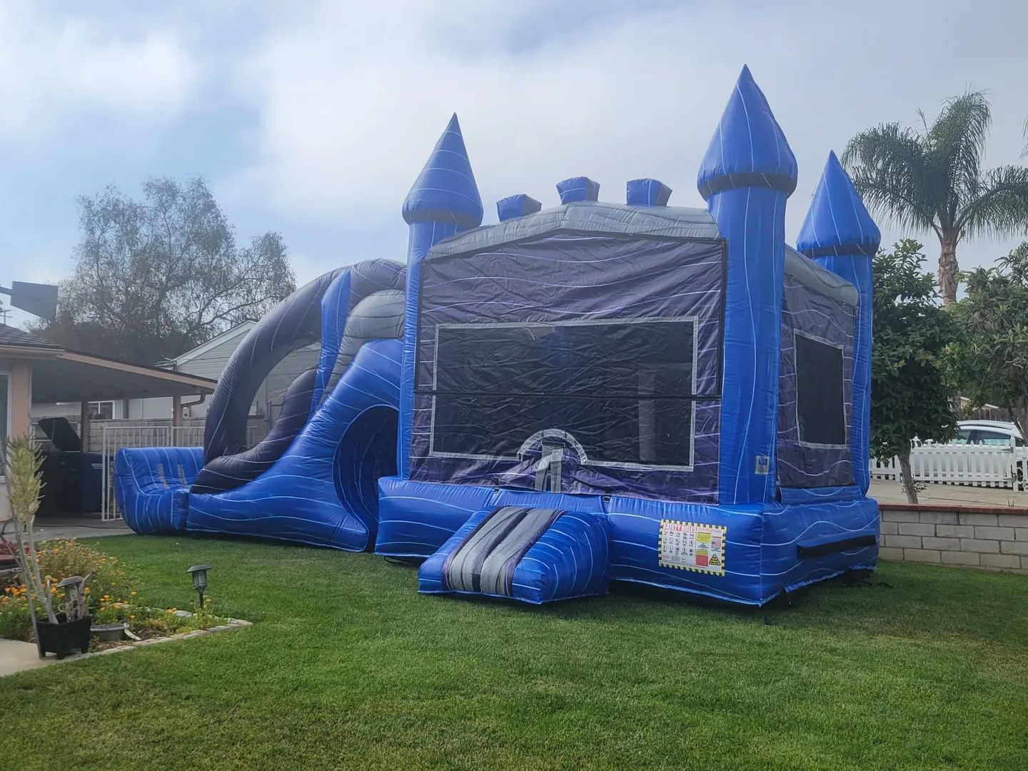A blue and black inflatable castle with slide.