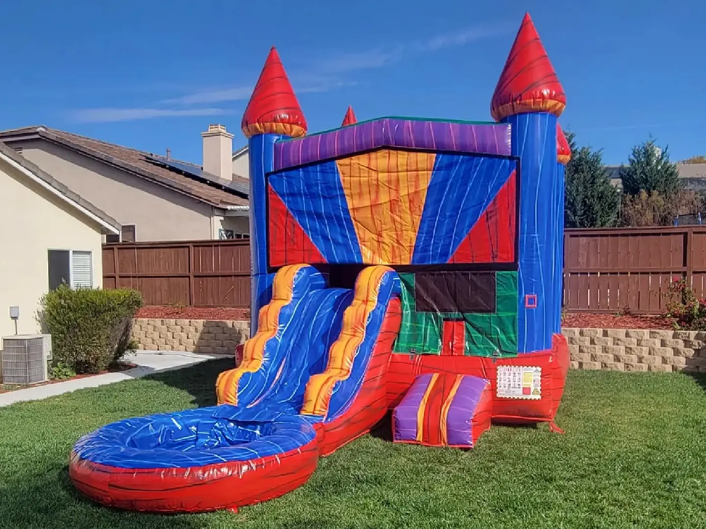 A red, blue and yellow inflatable castle with water slide.