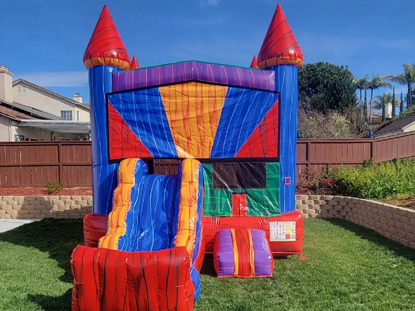 A colorful inflatable castle with slide in the yard.