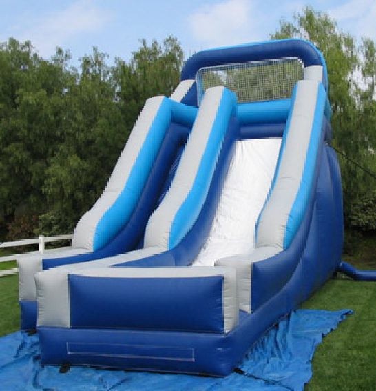 A blue and white inflatable slide in the grass.