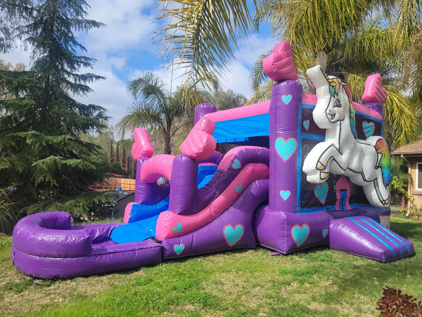 A pink and purple inflatable slide with a unicorn on it.