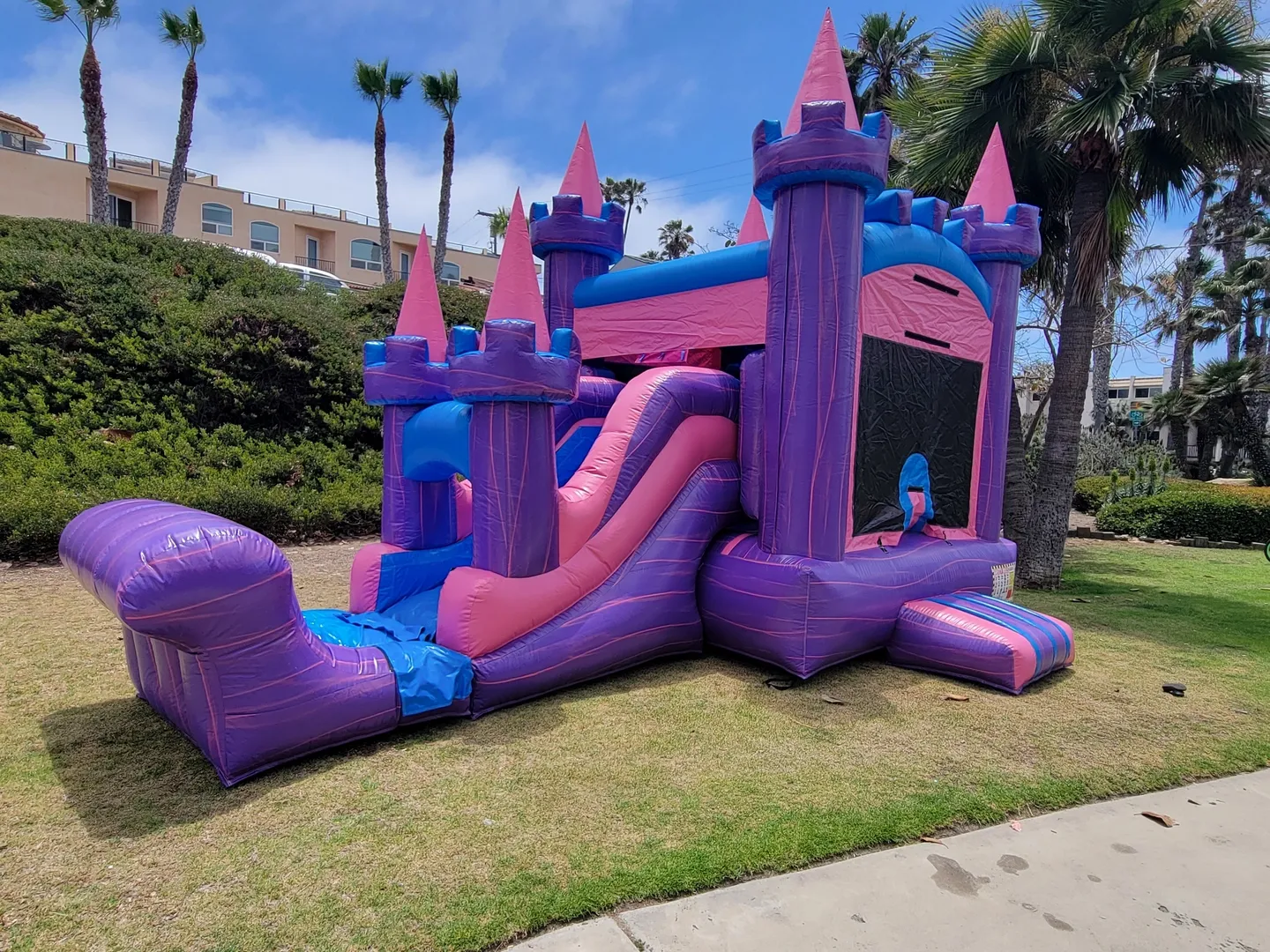 A purple and pink inflatable castle with slide.