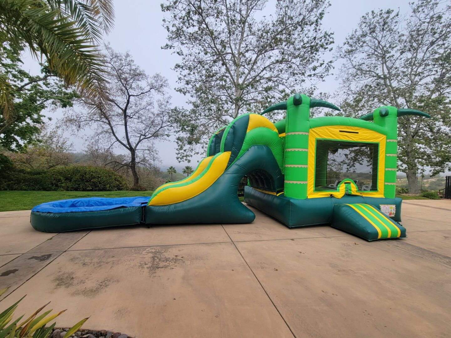 A green and yellow inflatable slide with water.