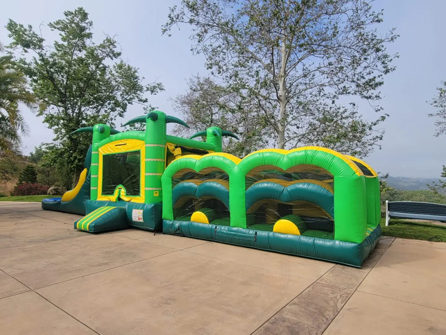 A green and yellow inflatable obstacle course set up in the yard.