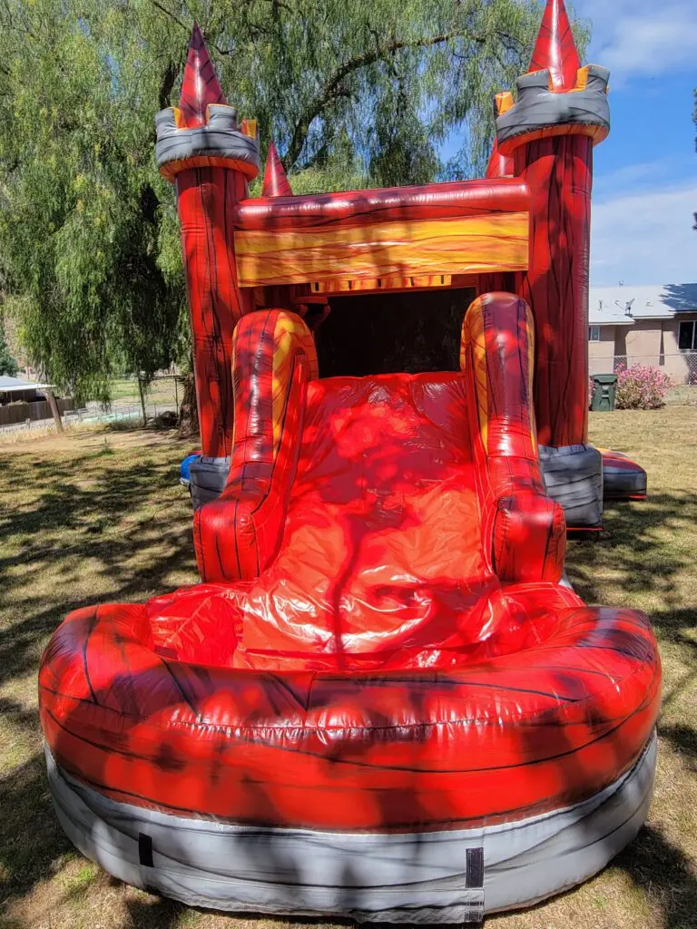 A red and black inflatable slide in the grass.