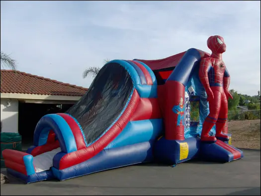 A spiderman inflatable slide and bouncer in the yard.