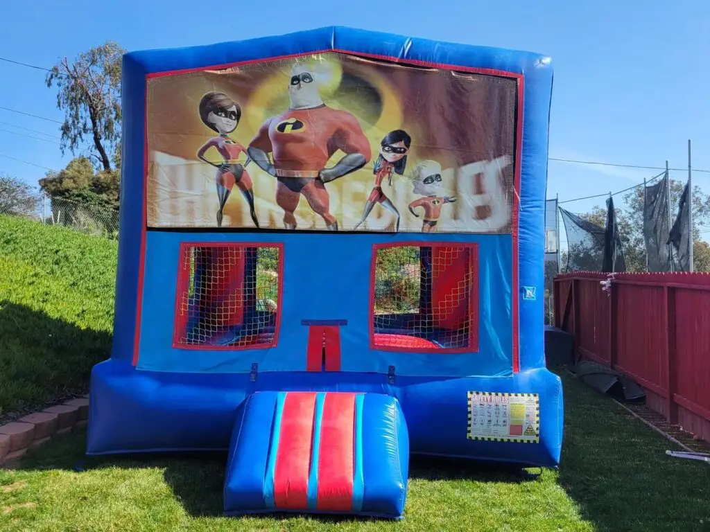 A blue and red inflatable bounce house with the incredibles on it.
