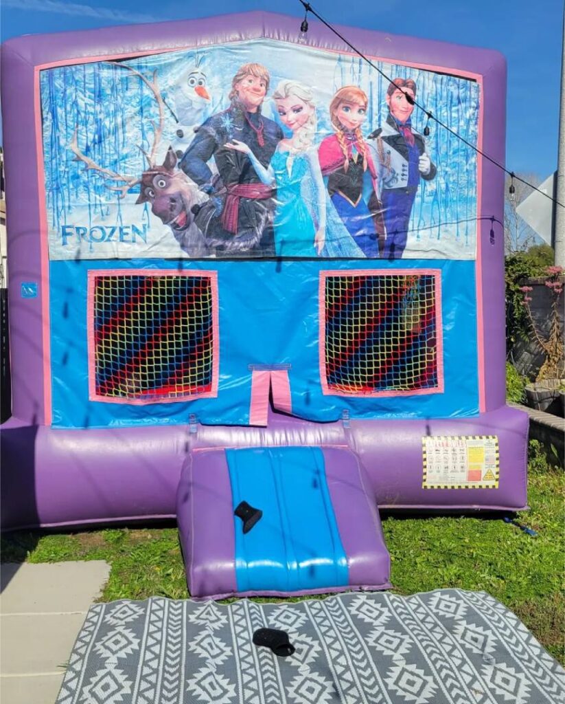 A frozen bounce house with a bench in the grass.