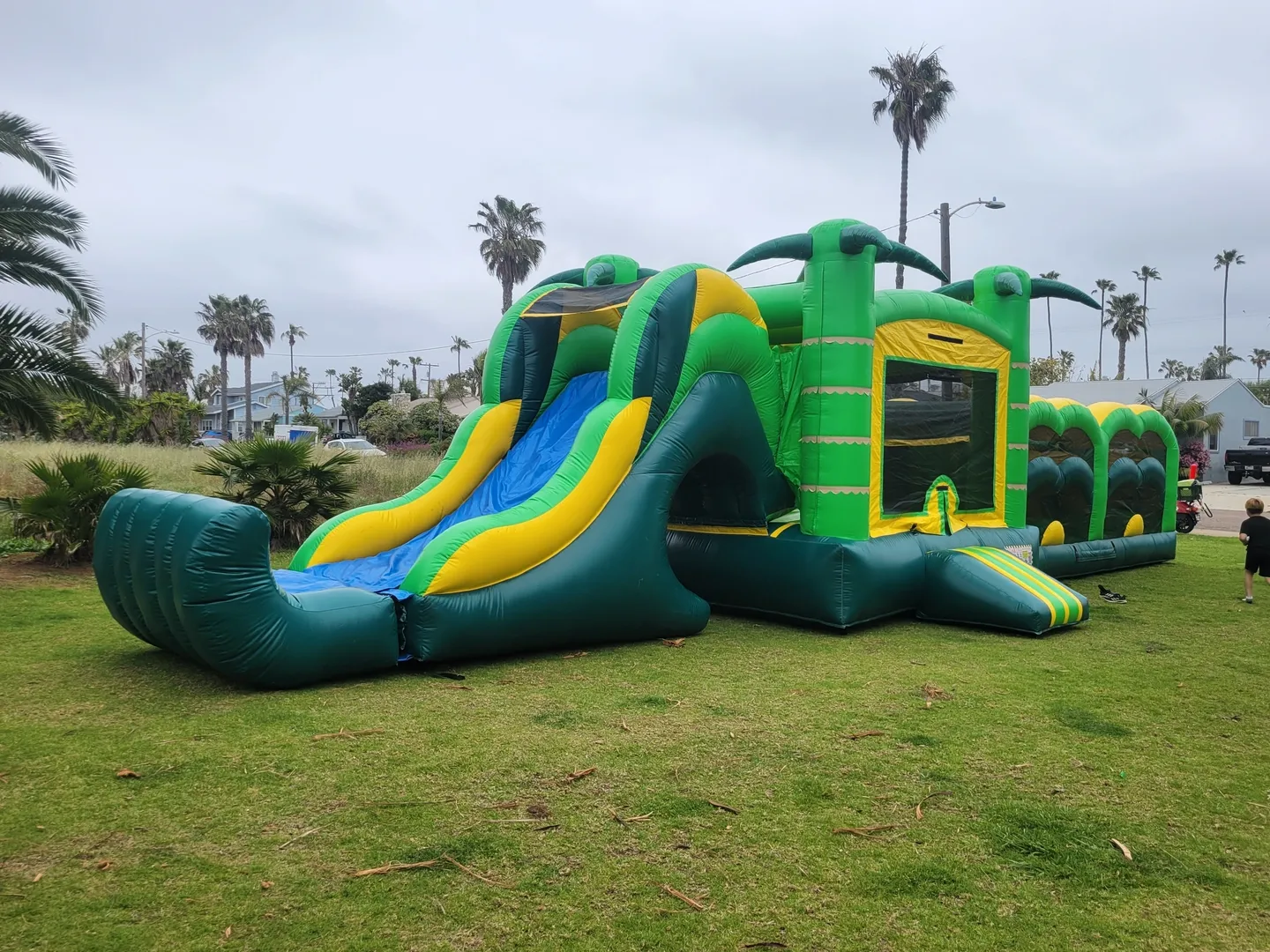 A green and yellow inflatable slide in the grass.