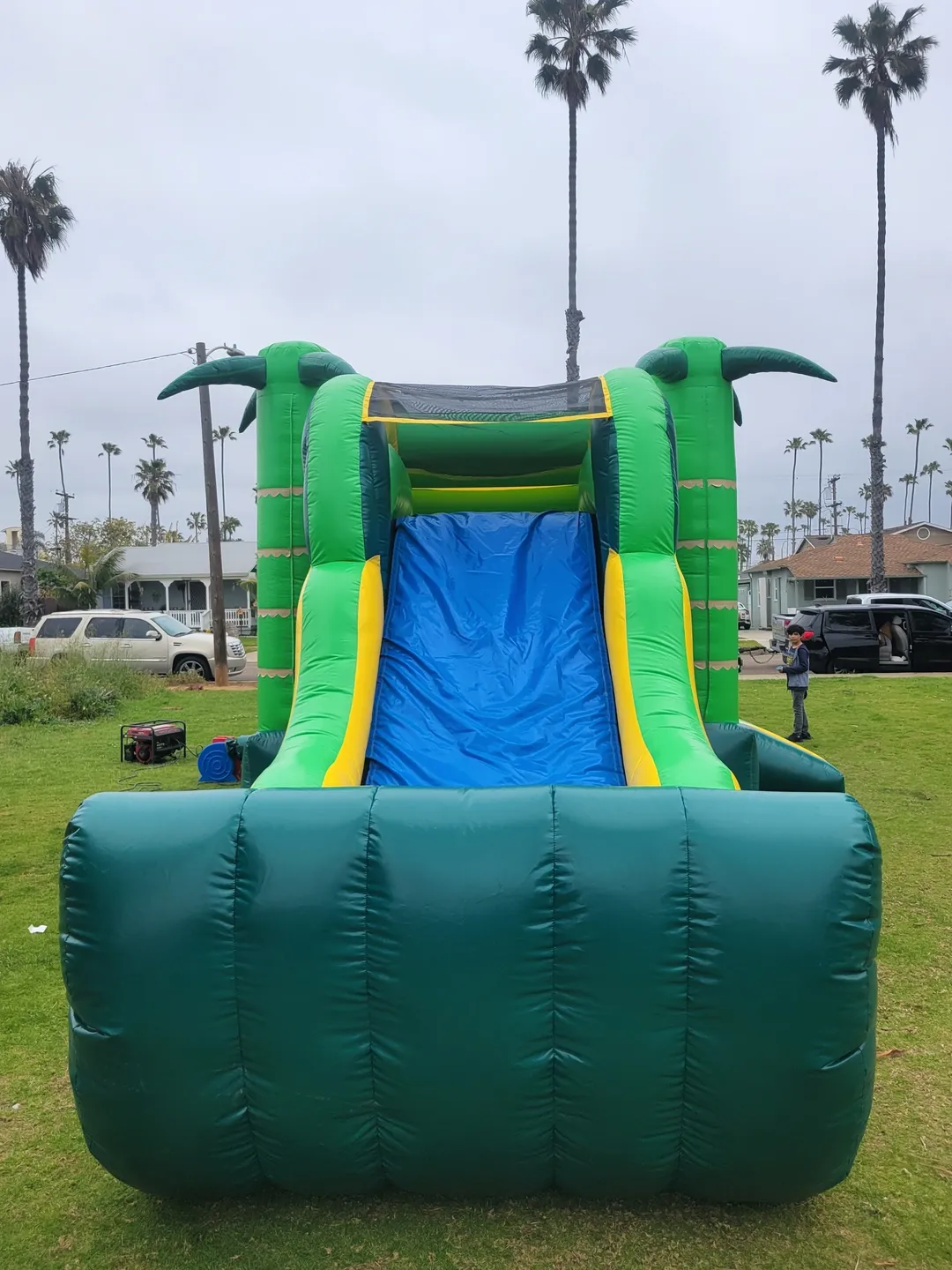 A green and blue inflatable slide in the grass.