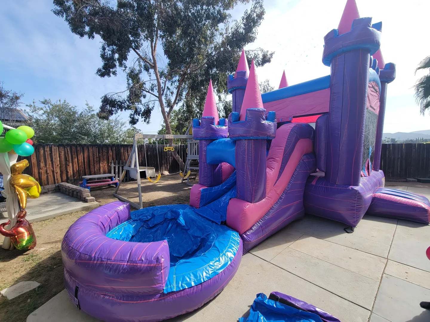 A purple and blue inflatable castle with water slide.