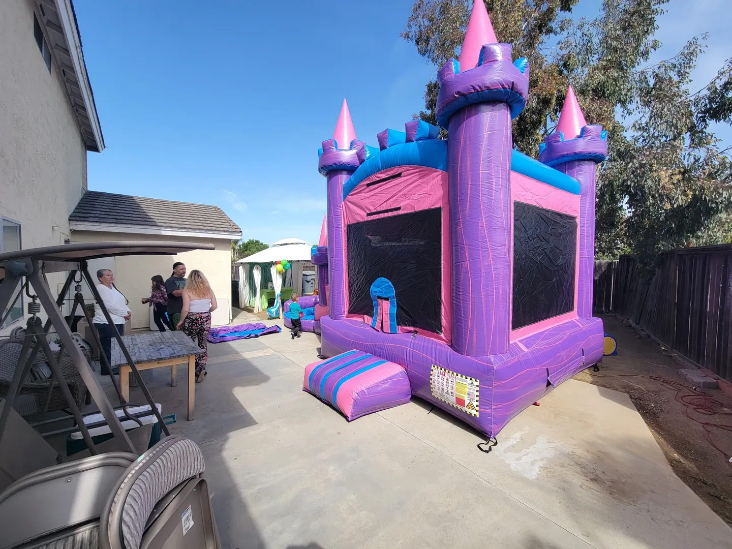 A purple and pink inflatable castle with people in the background.