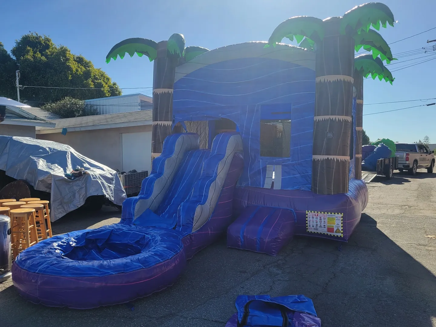 A blue and purple inflatable slide with palm trees.