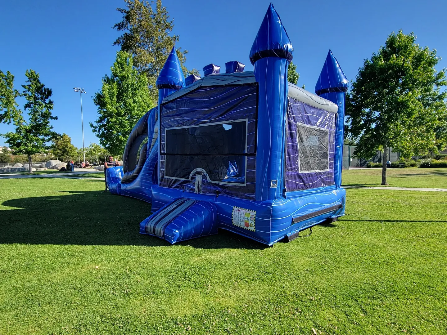A blue and silver bouncy castle in the middle of a park.